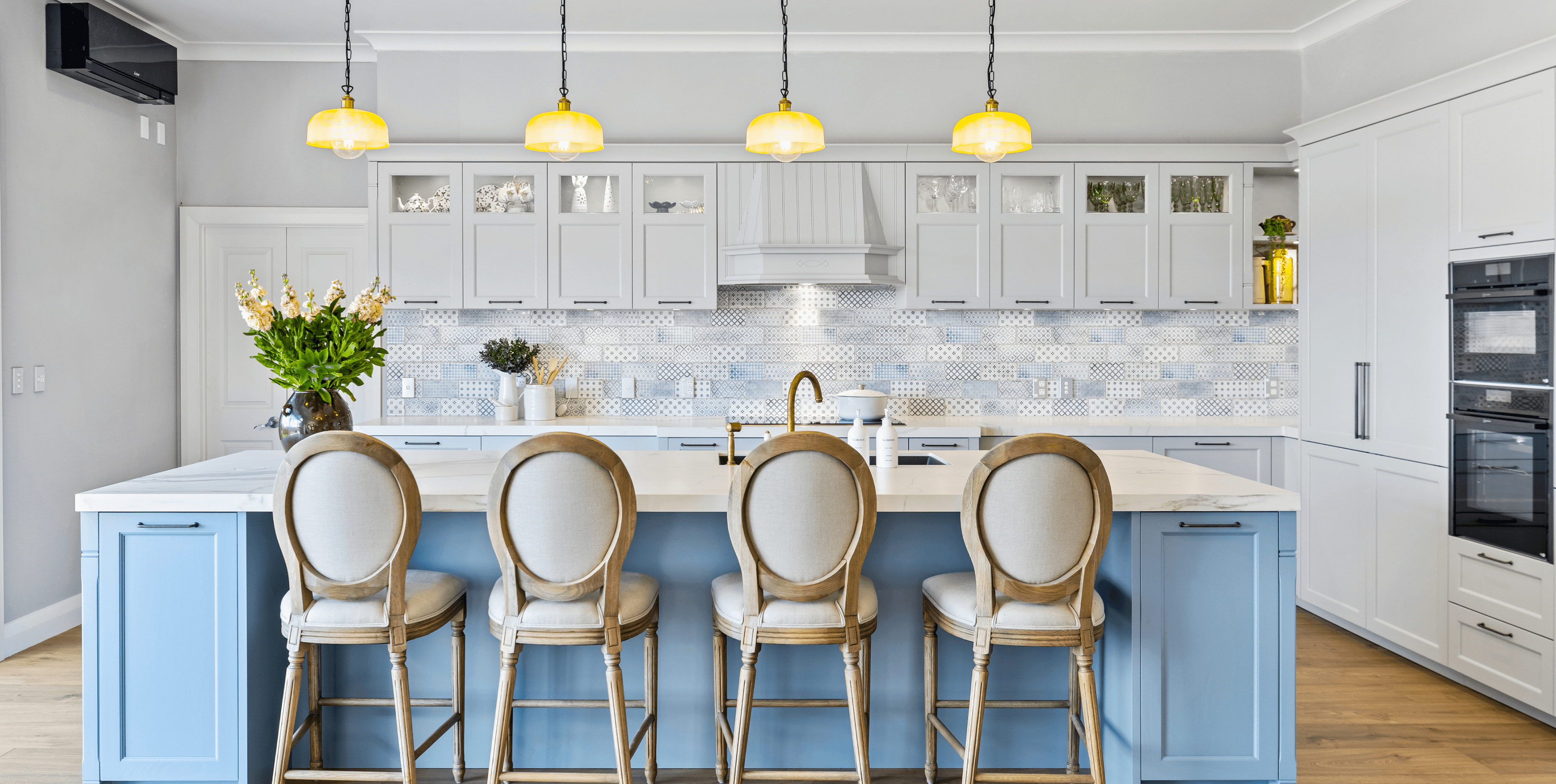 Bright, traditional kitchen in blue and white tones with detailed tiling and gold accents for warmth.