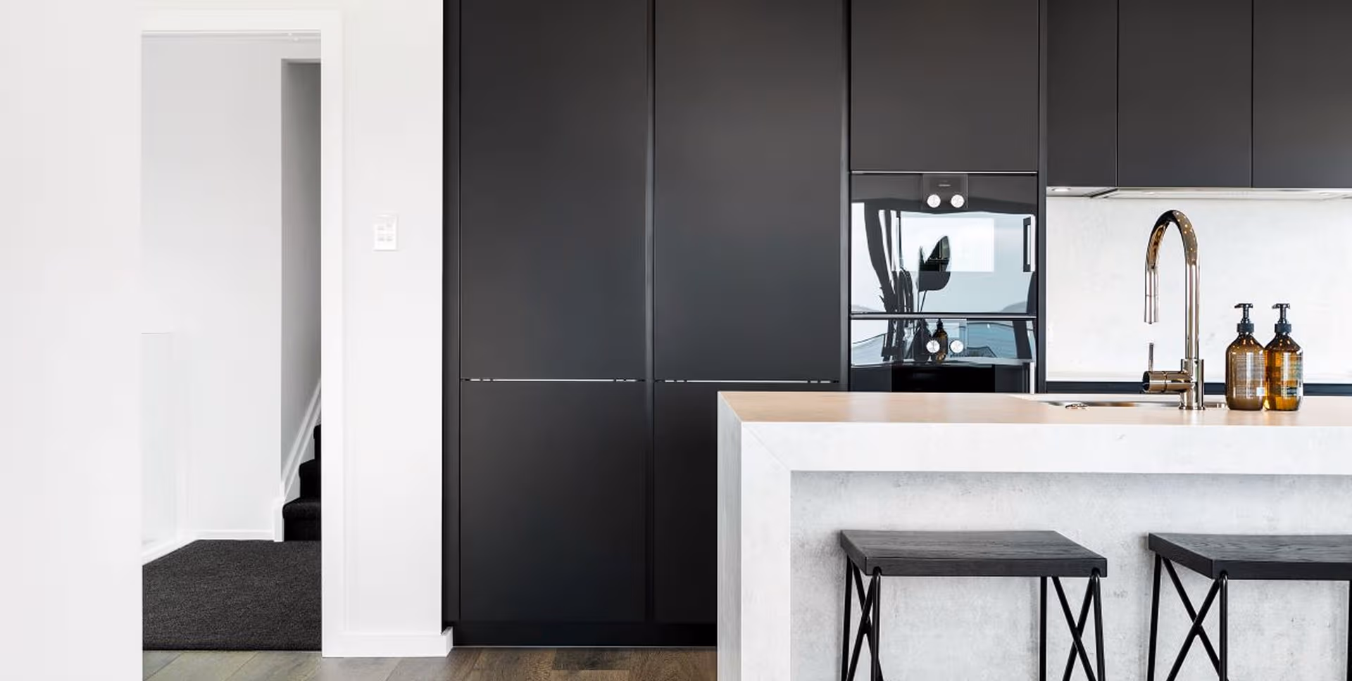 Matte black cabinetry meets soft stone surfaces for a look that's precise, balanced and effortlessly modern.