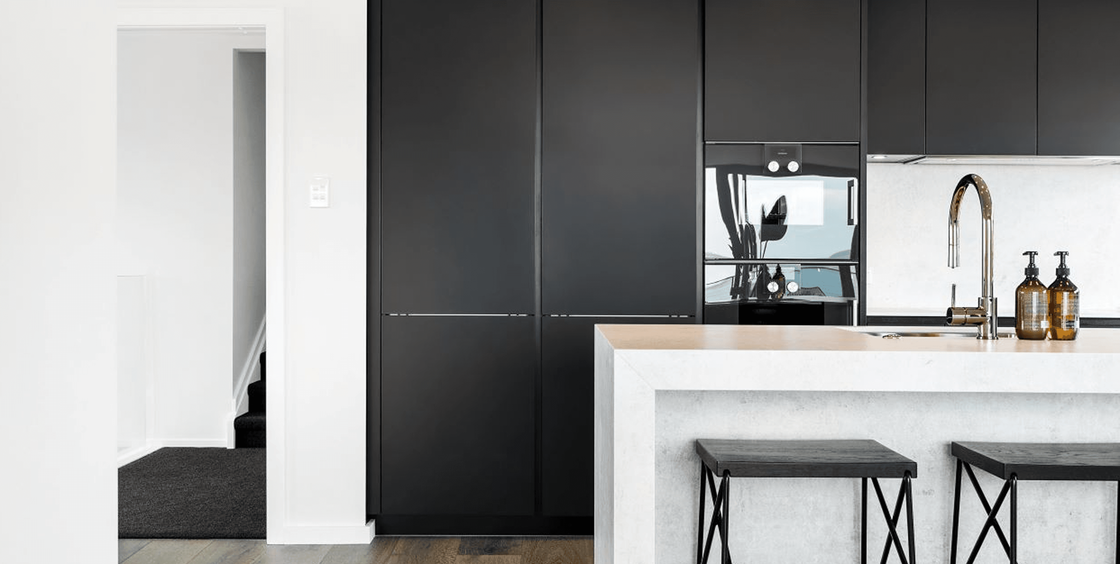 Matte black cabinetry meets soft stone surfaces for a look that's precise, balanced and effortlessly modern.