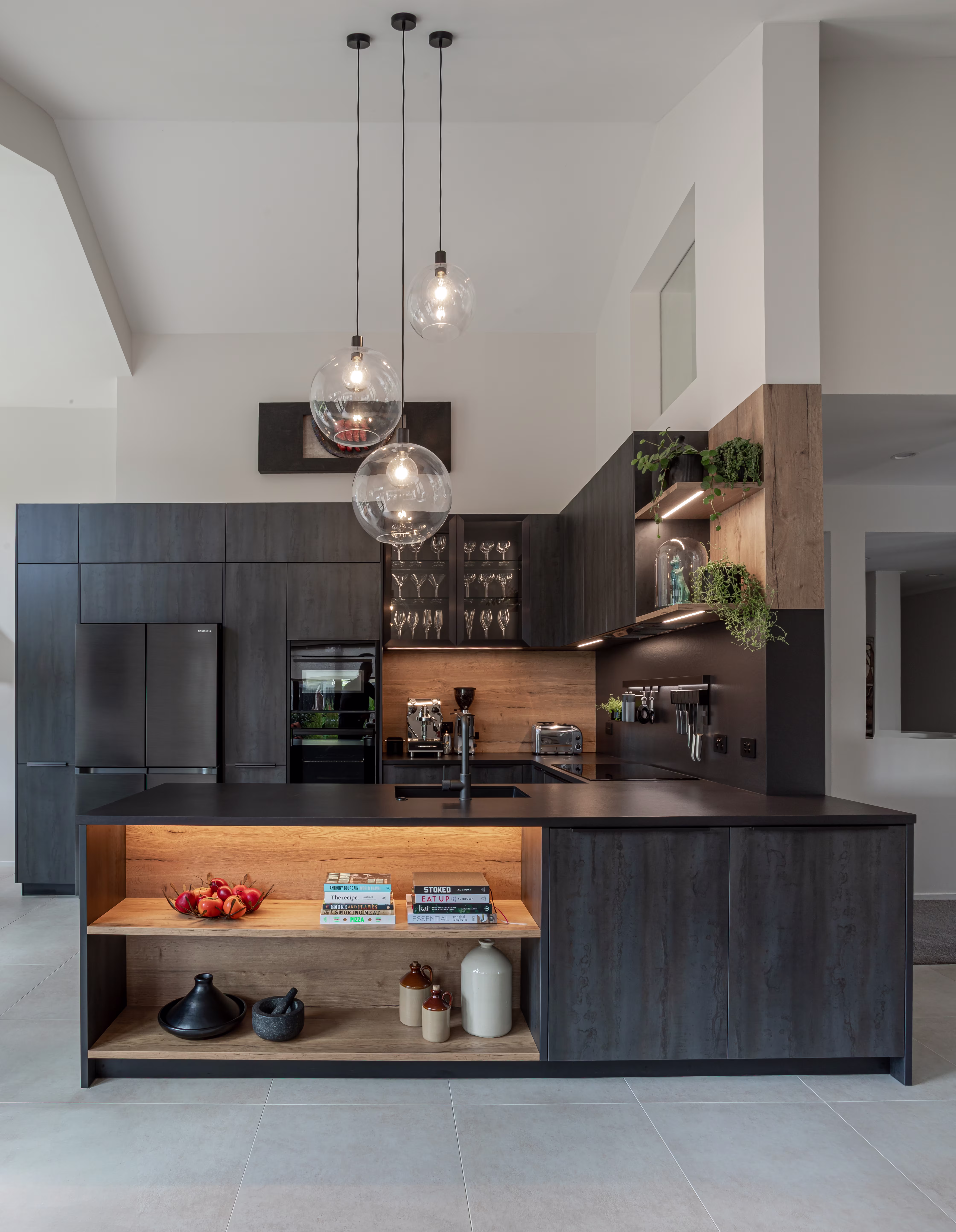 A sculpted island in dark tones and soft stone becomes the focal point of a refined, modern kitchen.
