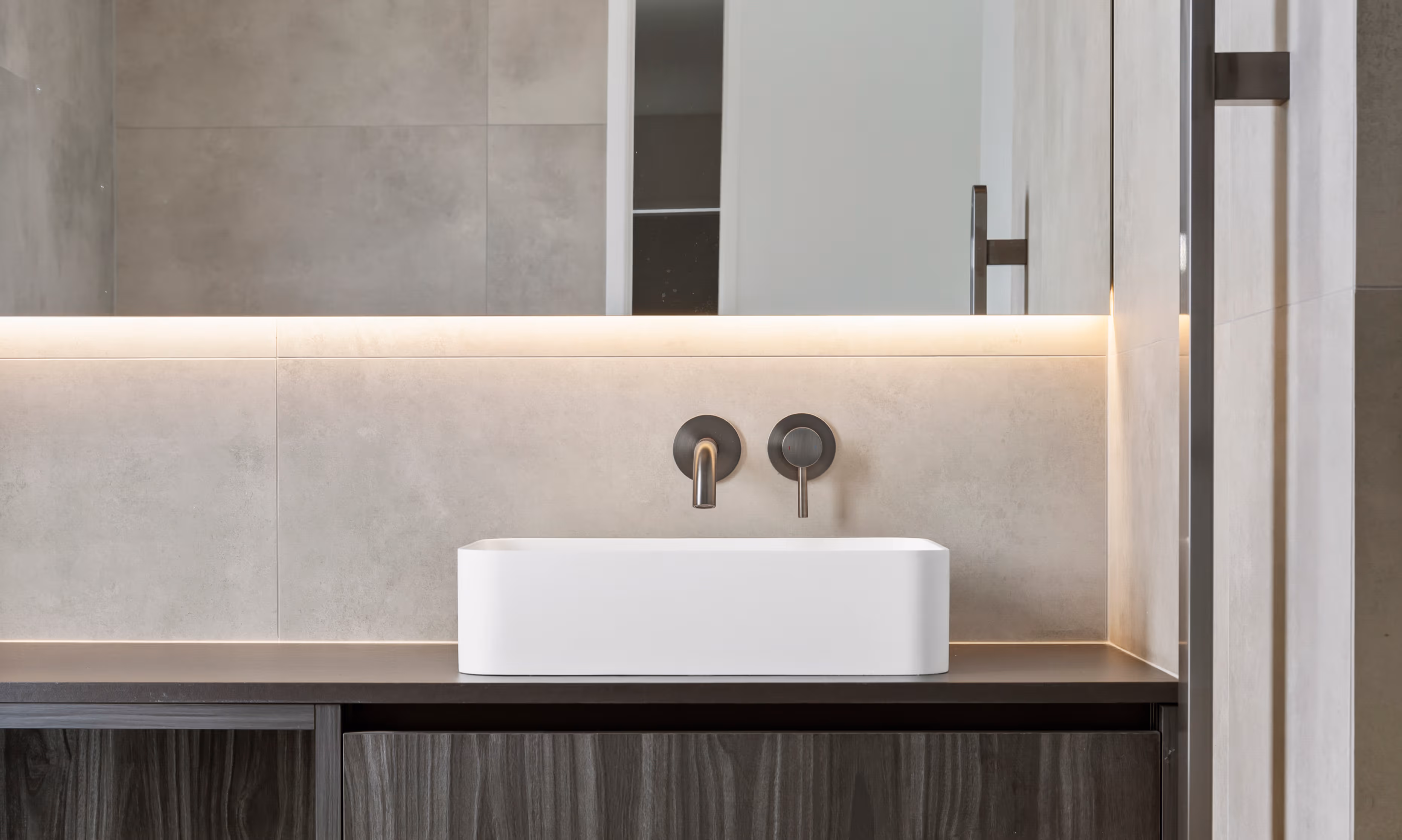 The brushed brass tap is colour-matched to the vanity, creating a warm accent against the marble backdrop.