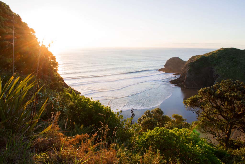 Sunset over mountains with crashing waves in the background